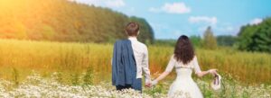 Svatební pár v přírodě na louce se drží za ruce