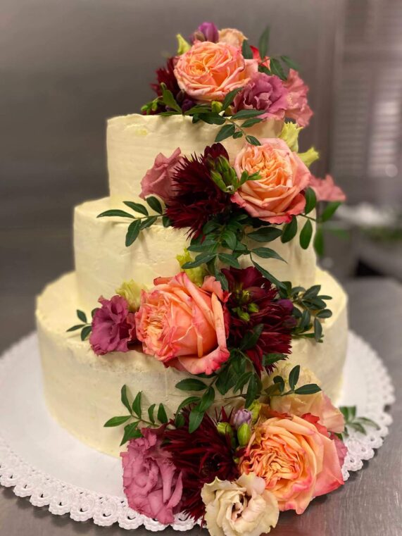 Třípatrový dort zdobený barevnými růžemi z Café Mozart