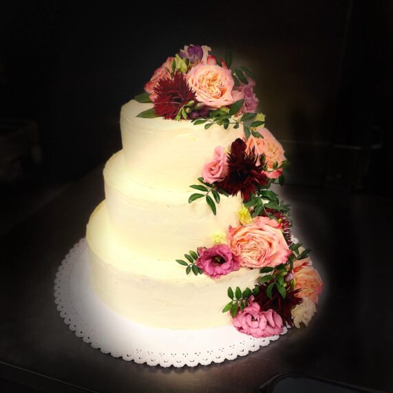Třípatrový dort zdobený barevnými růžemi z Café Mozart