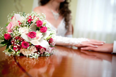 Svatební kytice v pozadí spojené ruce