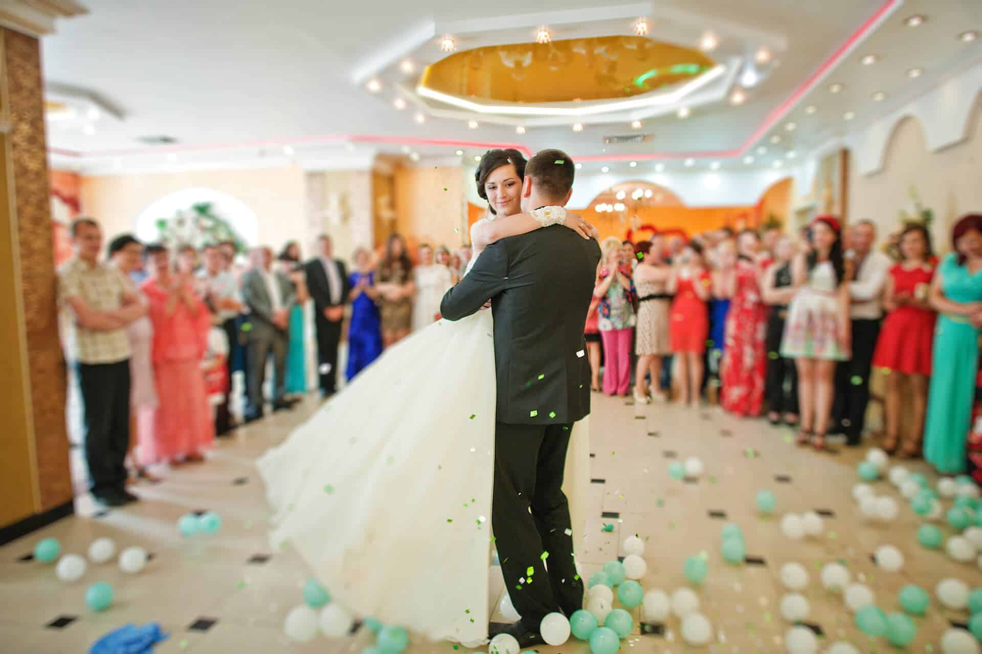 Novomanželé při svatebním tanci v kruhu svatebčanů