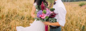 Nevěsta a ženich pozující na poli drží svatební kytici