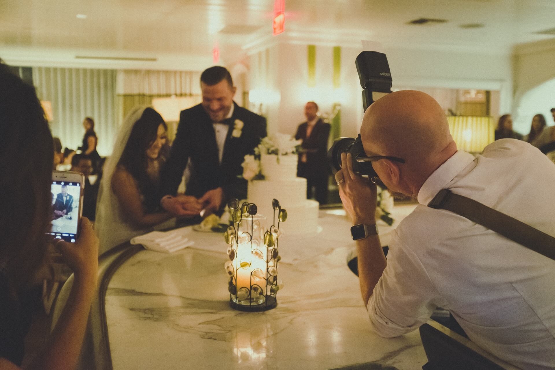 Svatební fotograf fotí pár při krájení dortu